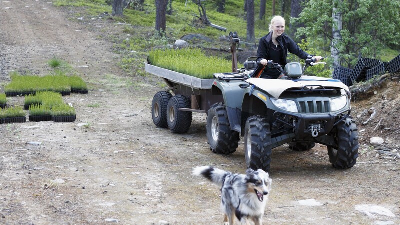Woman on quad bike with dog running next to her