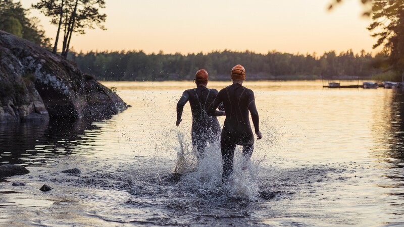Two people run into the water at dusk
