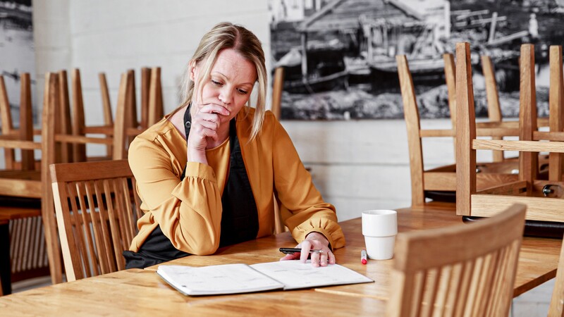 En kvinna sitter vid ett bord och skriver i en anteckningsbok. 