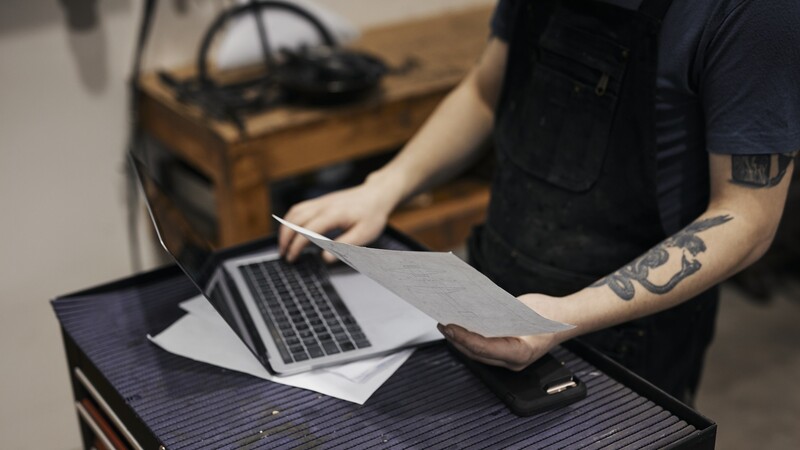 person with tattoo at laptop in workshop