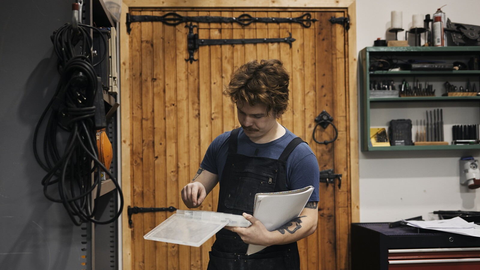 Craftsman in workshop looking in a plastic box